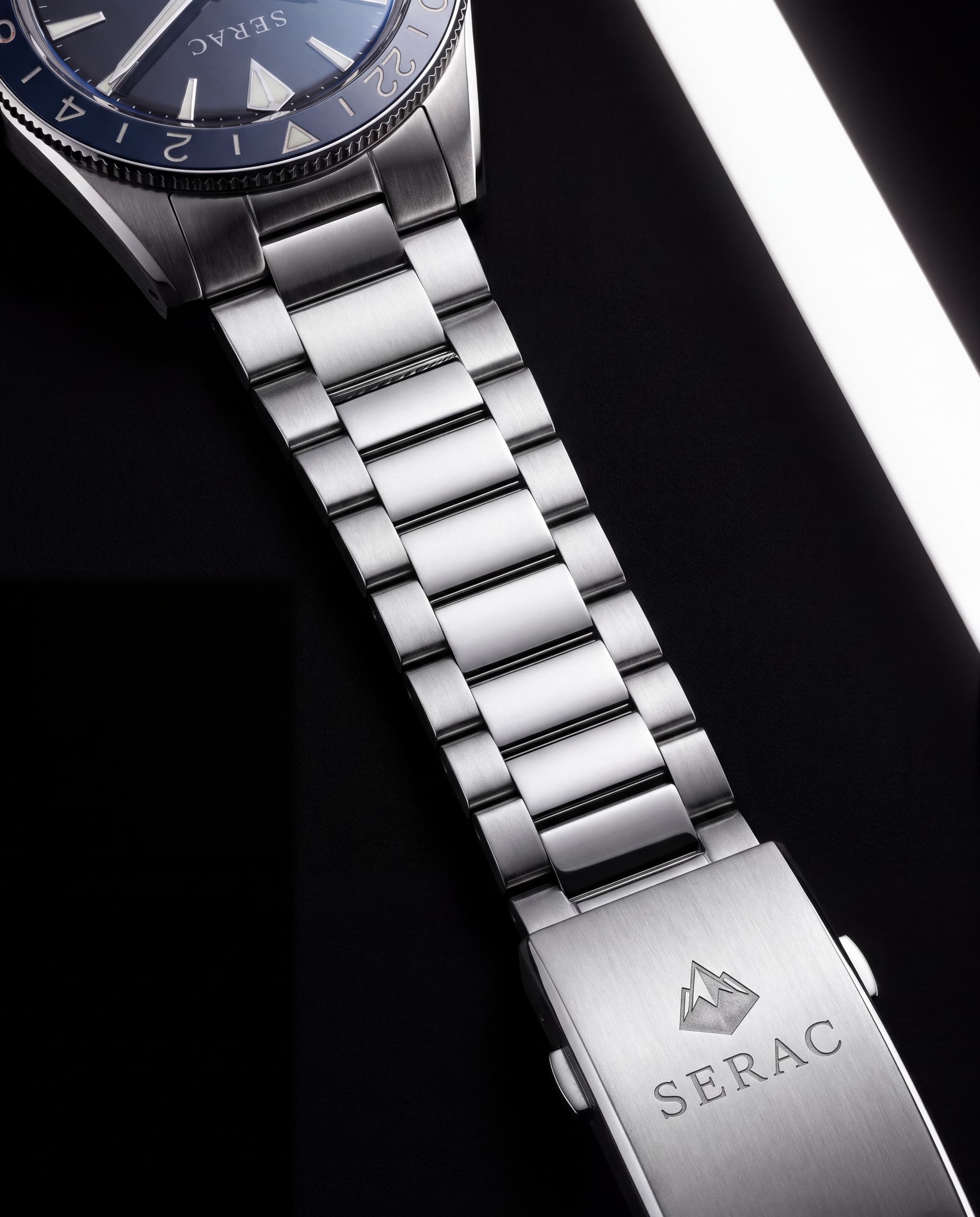 The Moraine three-row steel bracelet falling away from the case, its folding clasp engraved with the peak emblem and SERAC.